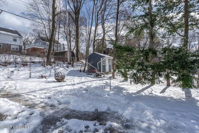 yard layered in snow featuring a storage shed and an outbuilding