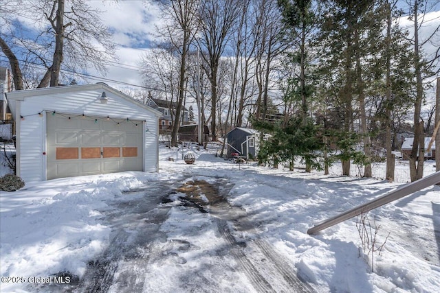 snowy yard featuring a garage and an outdoor structure