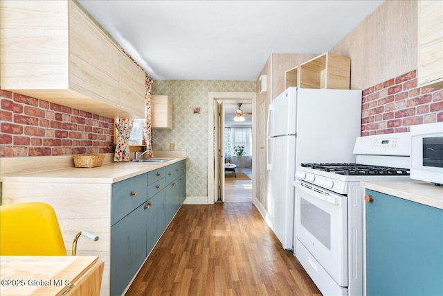 kitchen featuring blue cabinetry, light countertops, dark wood-type flooring, white appliances, and wallpapered walls