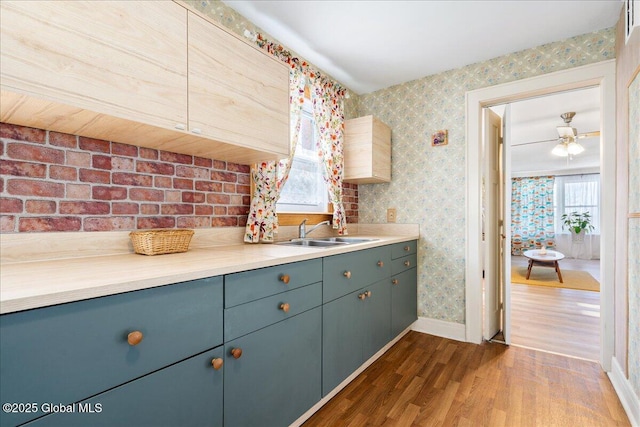 kitchen featuring dark wood-style floors, light countertops, a sink, baseboards, and wallpapered walls