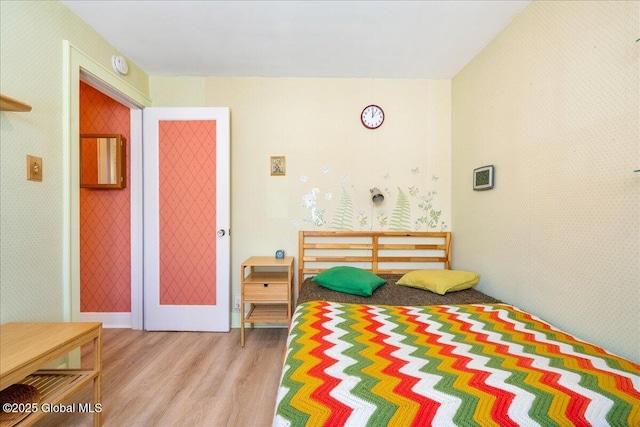 bedroom with wood finished floors and wallpapered walls