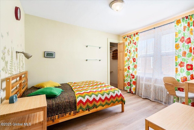 bedroom with wallpapered walls and wood finished floors