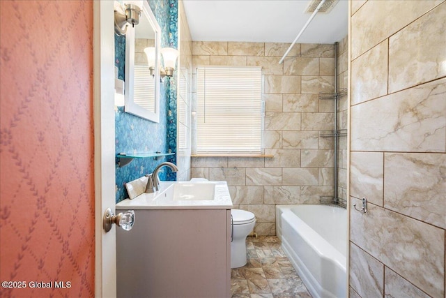 bathroom featuring visible vents, toilet, vanity, washtub / shower combination, and tile walls