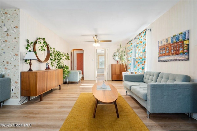 living area featuring ceiling fan, arched walkways, and wood finished floors