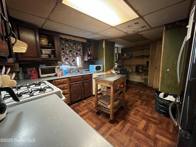 kitchen featuring sink, a drop ceiling, white appliances, and dark parquet flooring