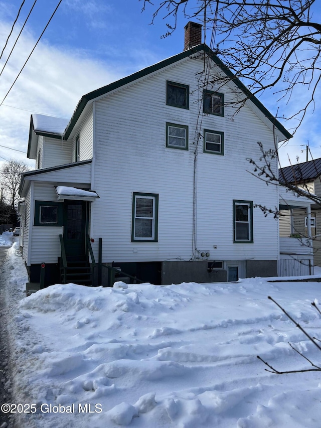 snow covered back of property with central AC