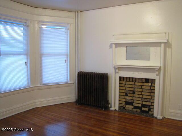 37-39 N Manning Blvd, Albany, NY 12206 - unfurnished living room featuring baseboards, plenty of natural light, radiator, and wood finished floors