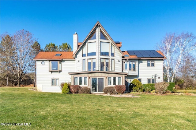 rear view of house featuring a yard and solar panels