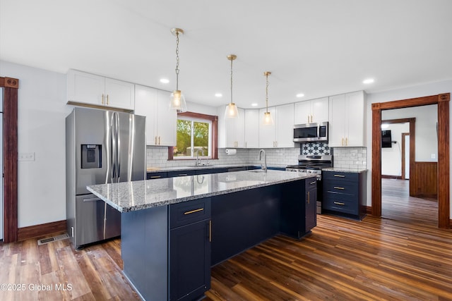 11208 State Route 22, Fort Ann, NY 12827 - kitchen with appliances with stainless steel finishes, dark wood-style flooring, a kitchen island with sink, baseboards, and white cabinetry