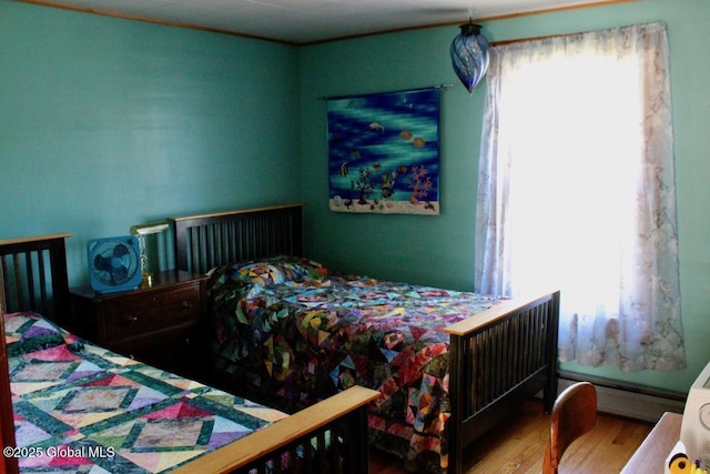 bedroom with baseboard heating and wood-type flooring