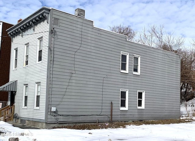 view of snow covered exterior featuring a chimney