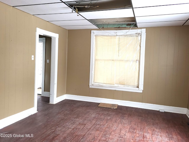 empty room with a paneled ceiling and dark hardwood / wood-style flooring