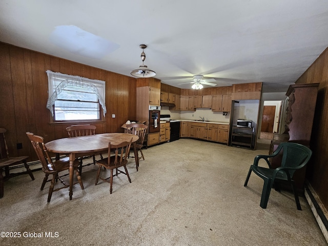 dining area featuring sink, ceiling fan, and wood walls