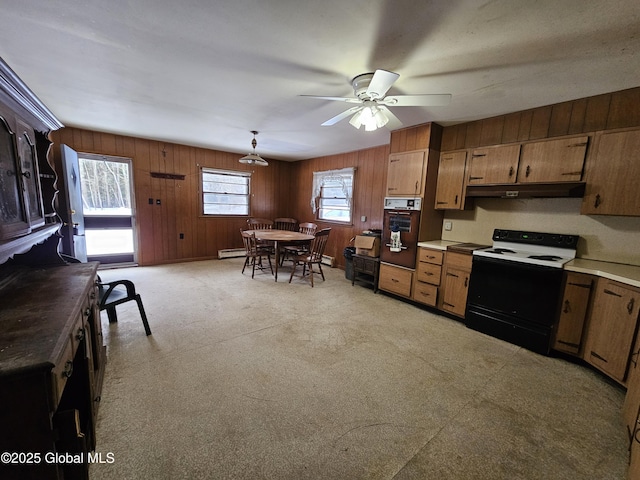 kitchen featuring pendant lighting, wooden walls, electric range, ceiling fan, and wall oven