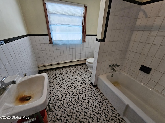 bathroom with tile patterned floors, toilet, sink, tile walls, and baseboard heating