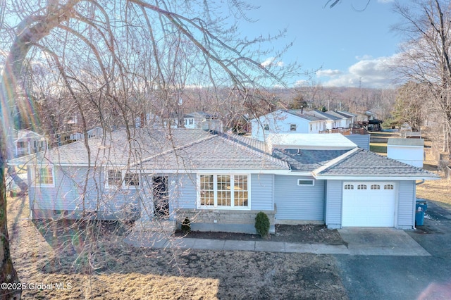 view of front of home featuring a residential view, driveway, an attached garage, and a shingled roof