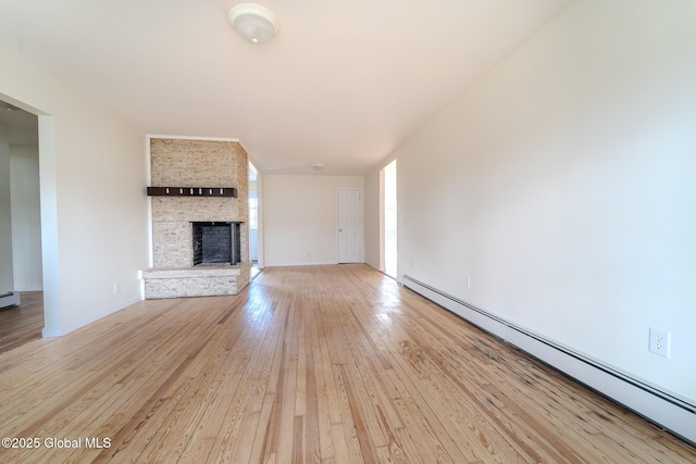 unfurnished living room featuring a large fireplace, light wood-style flooring, and a baseboard heating unit