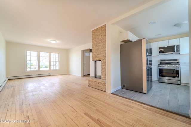 unfurnished living room with light wood-style flooring, a fireplace, baseboards, and a baseboard radiator