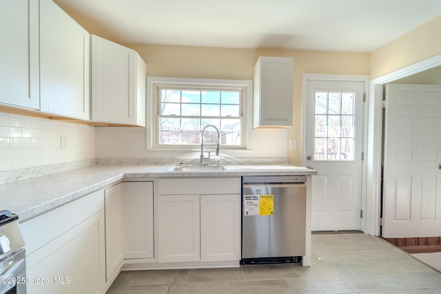 kitchen with a sink, a healthy amount of sunlight, white cabinets, and stainless steel dishwasher