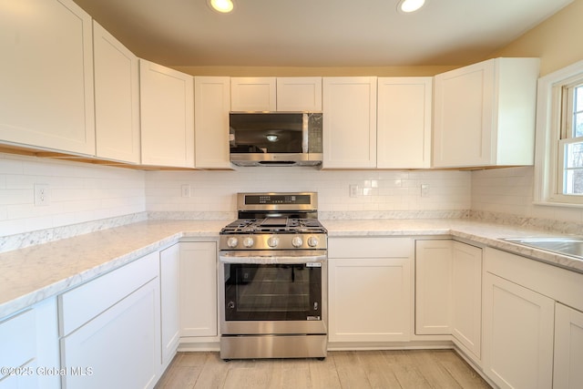 kitchen featuring tasteful backsplash, recessed lighting, light wood-style flooring, and appliances with stainless steel finishes