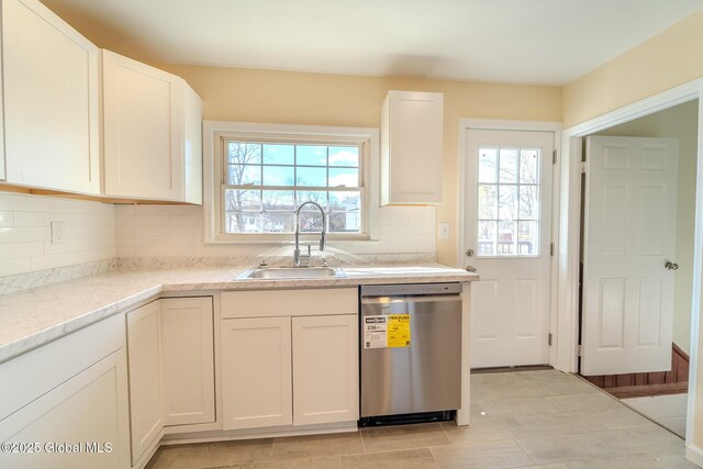 kitchen featuring tasteful backsplash, dishwasher, light stone counters, white cabinets, and a sink