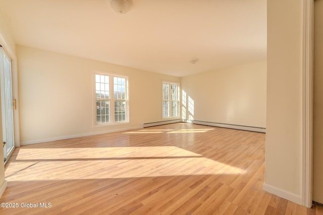 empty room featuring light wood-style flooring, baseboards, and a baseboard radiator