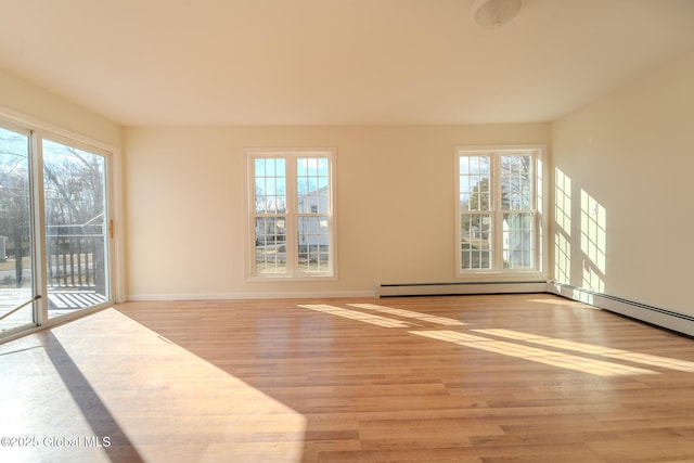 unfurnished room featuring a wealth of natural light, a baseboard radiator, baseboards, and light wood-style floors