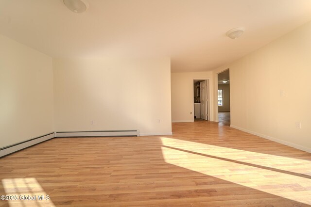 empty room with light wood-style flooring, baseboards, and baseboard heating