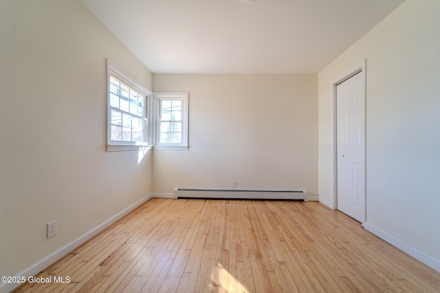 unfurnished bedroom with hardwood / wood-style floors, a closet, baseboards, and baseboard heating