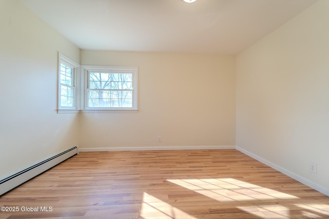 empty room featuring light wood-type flooring, a baseboard heating unit, and baseboards