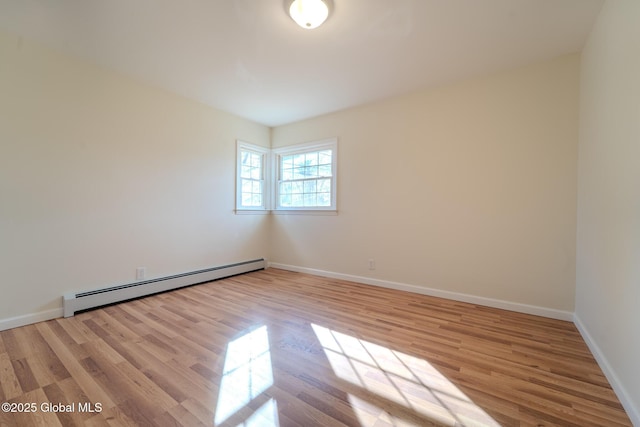 spare room with wood finished floors, baseboards, and baseboard heating