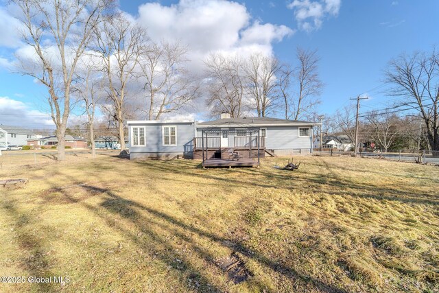 rear view of house with a yard, fence, and a wooden deck