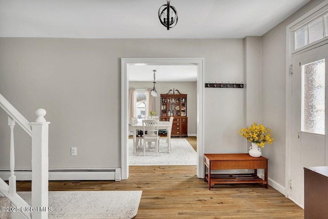 entrance foyer with light wood-style flooring, a baseboard heating unit, stairway, and baseboards