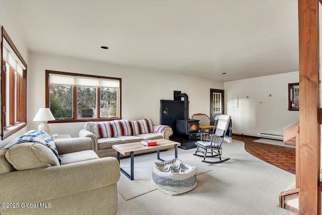 living area with a baseboard heating unit and a wood stove