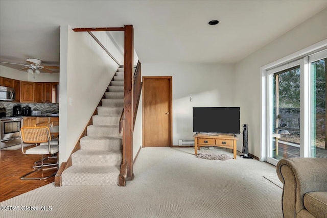 carpeted living room with baseboards, stairway, and baseboard heating