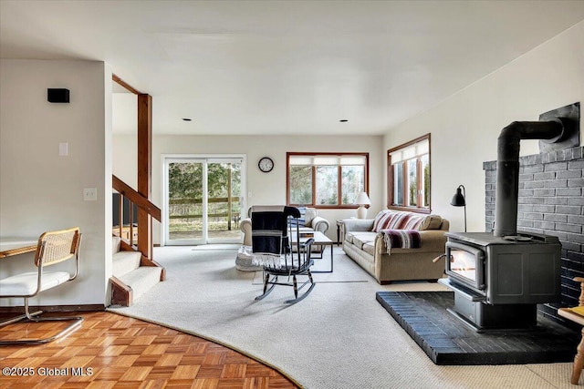 living area featuring a wood stove, stairway, and baseboards