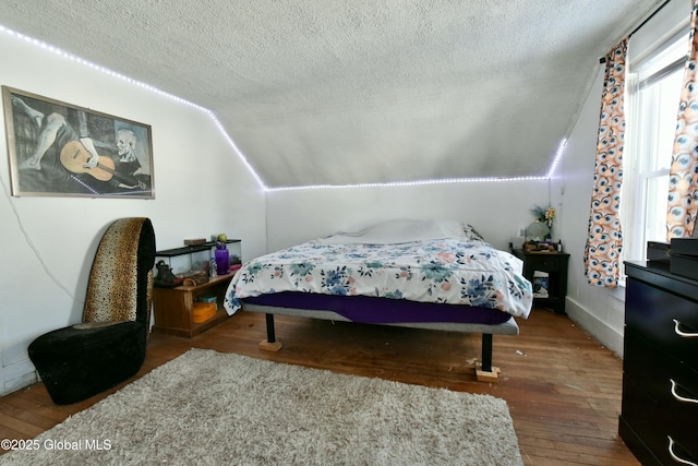 bedroom with lofted ceiling, dark hardwood / wood-style flooring, and a textured ceiling