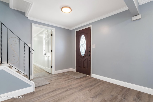 entrance foyer with ornamental molding, baseboards, stairs, and light wood-style floors