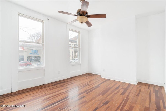 spare room with a ceiling fan, baseboards, and wood finished floors