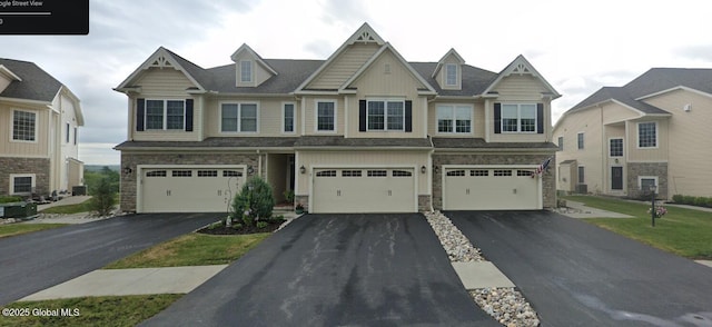 view of front of house with stone siding, central AC, an attached garage, and driveway