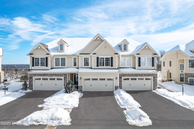 view of front of property featuring a garage, stone siding, driveway, and board and batten siding