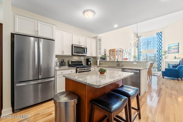 kitchen with stainless steel appliances, white cabinets, glass insert cabinets, and a kitchen island