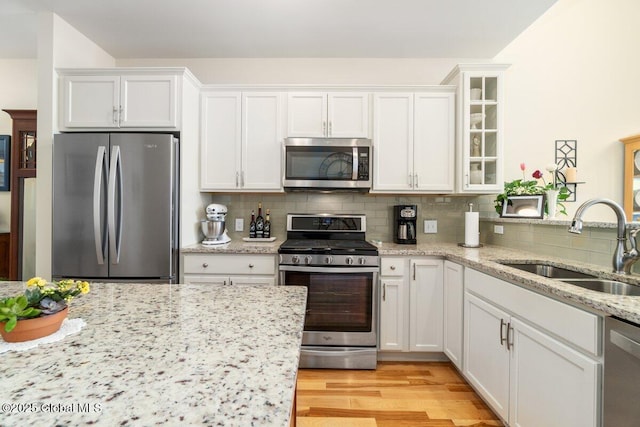 kitchen featuring glass insert cabinets, white cabinetry, appliances with stainless steel finishes, and a sink