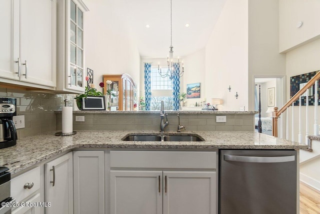 kitchen with glass insert cabinets, white cabinets, a sink, and stainless steel dishwasher