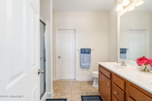 bathroom featuring double vanity, toilet, an enclosed shower, a sink, and baseboards