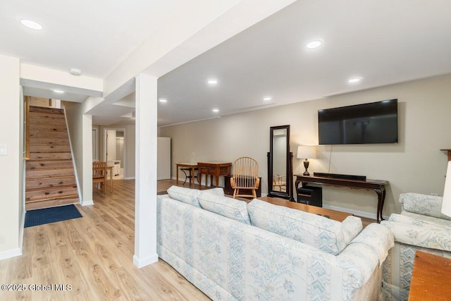 living room featuring stairs, recessed lighting, baseboards, and light wood-style floors