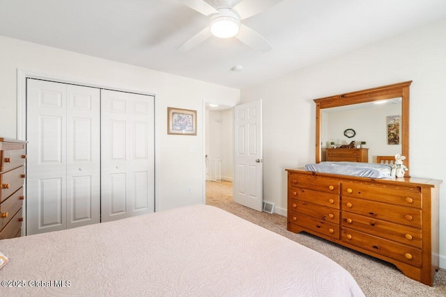 bedroom with a closet, visible vents, a ceiling fan, light carpet, and baseboards