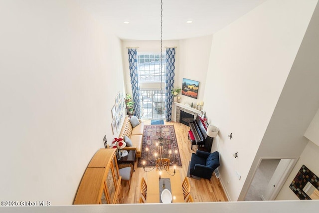 dining area featuring baseboards, wood finished floors, a fireplace, a notable chandelier, and recessed lighting