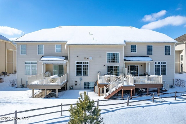 snow covered rear of property featuring fence, stairway, and a deck