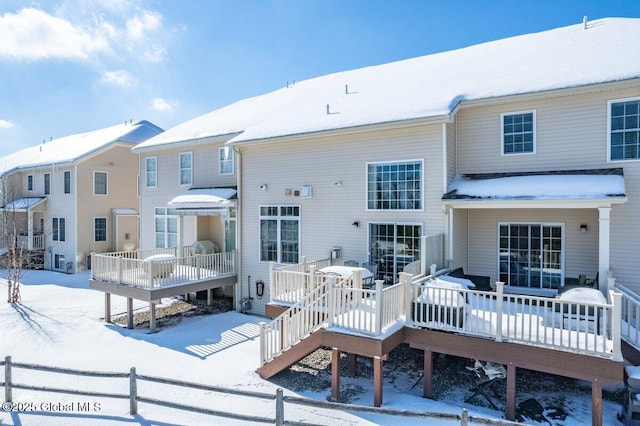 snow covered house with fence and a deck